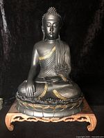 Front view of black and gold seated Buddha statue on lotus pedestal