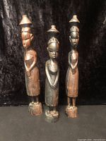 Front view of three carved ebony women statuettes