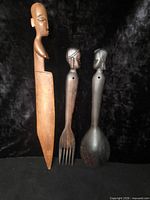 All three carved hardwood utensils standing upright against black background