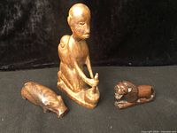 Group view of kneeling figure, hippo, lion carvings