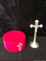 Pewter crucifix and red Masonic cap side by side