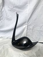 Front left view of glossy black porcelain swan