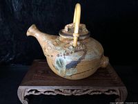 Right side view of signed Gravelle stoneware teapot on wooden stand