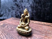 Front view of gold-plated Buddha couple figurine on wooden stand