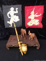 Full lot showing opium pipe, two fabric prints, two carved elephants on a wooden stand
