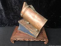 Left profile of copper bee smoker on stand showing bellows and nozzle