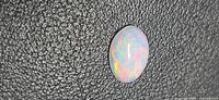Front view of oval Ethiopian opal showing body tone and play of color