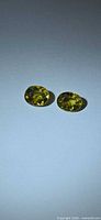 pair of oval yellow-green sphene gemstones on neutral background