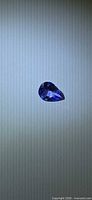 Pear cut violet-blue tanzanite centered on neutral background