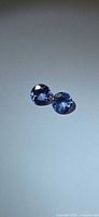 Pair of violet-blue round faceted tanzanites on neutral background