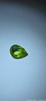 Pear checkerboard cut green peridot on light background