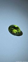 Front view of oval vivid green peridot on neutral background