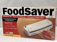 Front of sealed retail box showing FoodSaver VAC300 vacuum packaging system