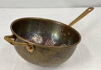 Copper colander side view showing brass long handle, loop handle and interior patina