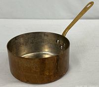 Side view of copper saucepan showing brass handle and rivets