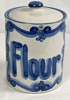 Front view of stoneware flour canister showing blue script and decorative border