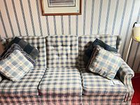 Front view of plaid three-seat sofa with pillows