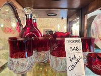 Front view of tumblers, decanter and cup showing ruby-flashed glass and engraved script