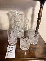 Pitcher and four tumblers on wooden surface