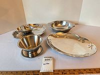 All five Wilton metal serveware pieces grouped on white backdrop with ruler for scale
