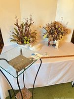 Overall lot showing plant stand, two floral arrangements and ceramic duck for scale and context