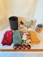 Overall lot showing napkins, napkin rings, metal cylinder, rooster figurines, jar candle