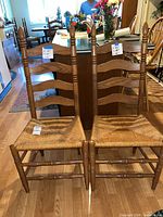 Front view of both ladder-back chairs showing wood finish and rush seats