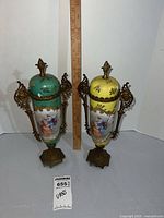 Front view of both porcelain urns beside ruler and lot card