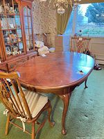 Oval dining table with one side chair visible, matching china cabinet background
