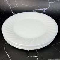 Stack of white swirl milk glass plates showing gloss and pattern