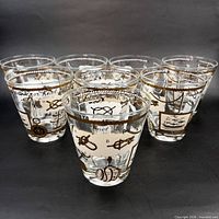 Group view of six of the eight gilt nautical tumblers