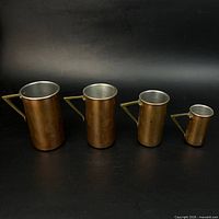 Front view of four graduated copper measures