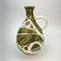 Front view of teardrop-shaped green and white abstract glaze vase with handle