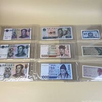 Fronts of Chinese yuan, Korean won, North Korean 100 won notes in binder