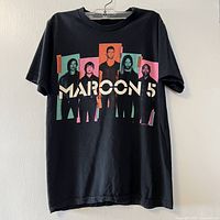 Full front view of black Maroon 5 graphic tee on hanger