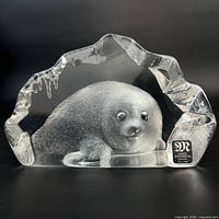 Front view of Mats Jonasson lead crystal baby seal paperweight showing original sticker and seal relief