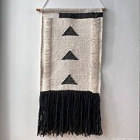 Full view of the woven wool wall hanging on dowel showing design and fringe