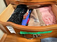 Drawer view showing five folded scarves and wraps
