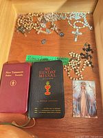 Drawer with books, rosaries, medals, holy card