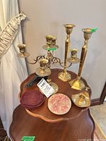 Full lot showing brass candlesticks, candelabra, chamberstick and cast-iron pieces on table