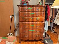 Front view of tall serpentine-front dresser showing six drawers and ornate handles