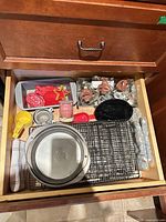 Drawer view showing cookie cutters, loaf pan, measuring cups, racks, cake pans, rolling pin, timer