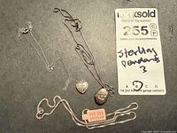 Overview of three sterling silver necklaces with pendants and MaxSold lot card