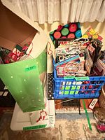 Large green bag and blue crate filled with assorted gift bags, wrap and tags