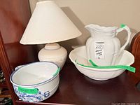 Group shot of lamp, white pitcher in basin, blue handled bowl