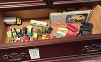 Drawer containing approximately 25–30 small die-cast vehicles including boxed Rolls Royce, double-decker bus, dump truck and assorted cars