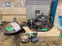 All five silverplate pieces shown together on countertop; tray in box, teapot, sugar, creamer, oval covered dish