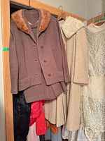 Closet shot showing brown jacket and skirt plus beige coat