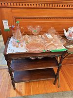 Full view of wooden side table with two lower shelves, glassware on top not included