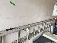 Full length of aluminum extension ladder mounted on wall